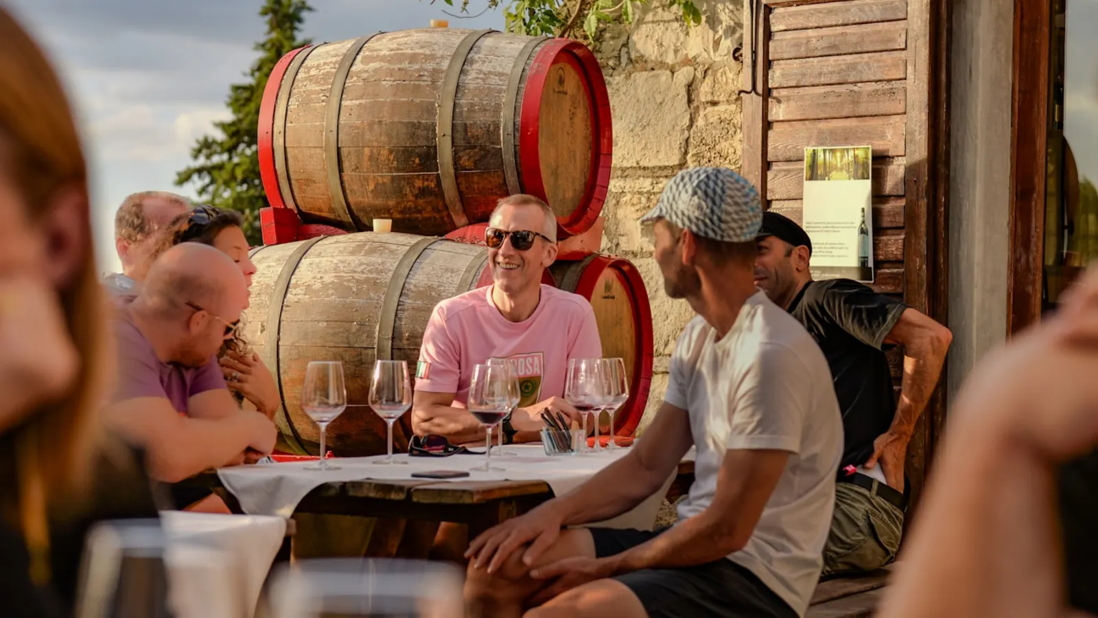 Guests enjoying a tasting beside barrels at a winery